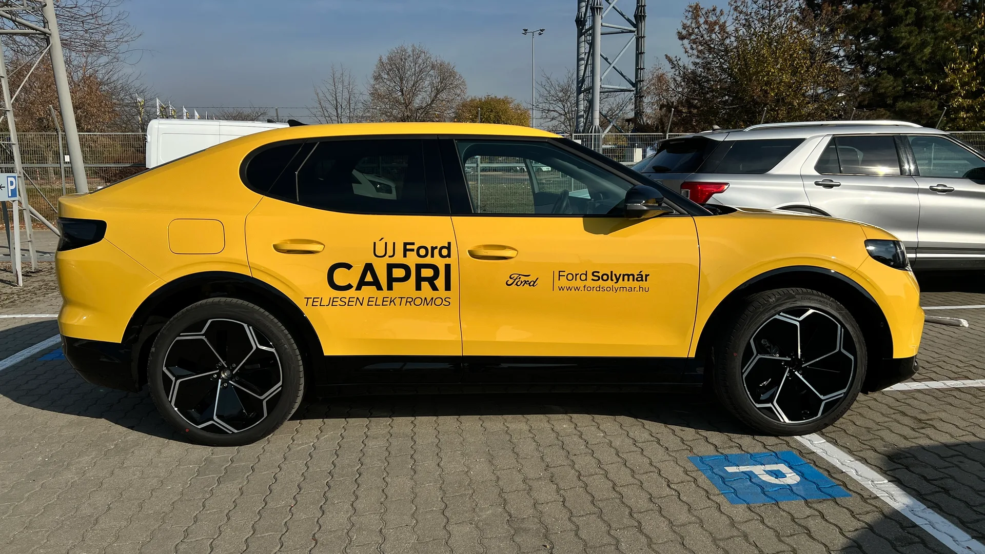 Sárga Ford Capri demóautó fekete vágott dekorációval – Új Ford Capri, Teljesen elektromos és Ford Solymár feliratokkal